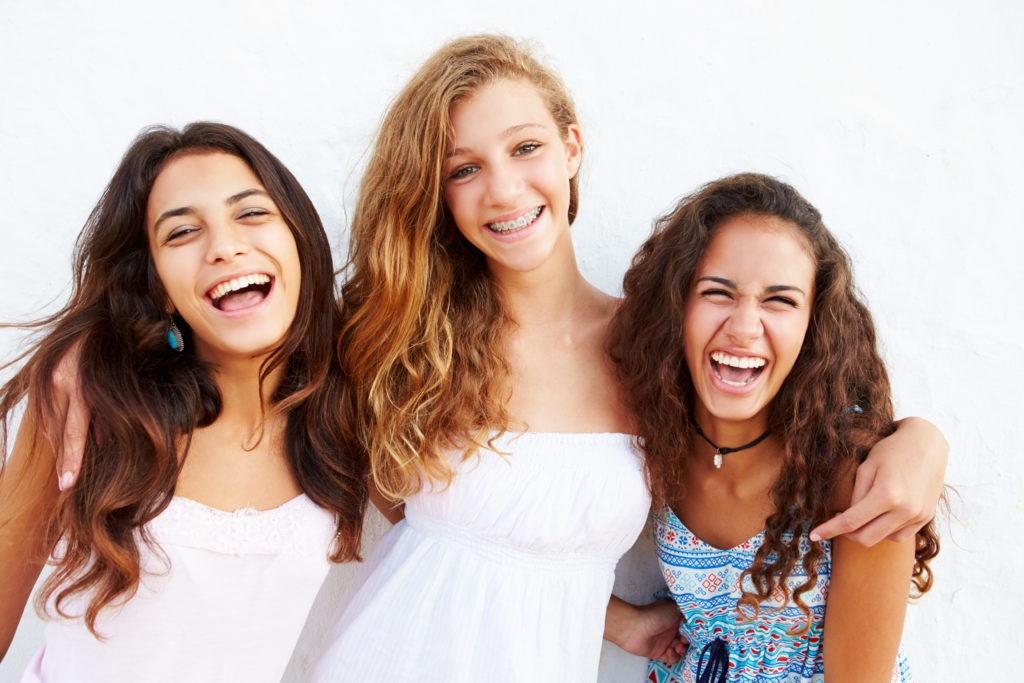 Portrait Of Three Teenage Girls Leaning Against Wall