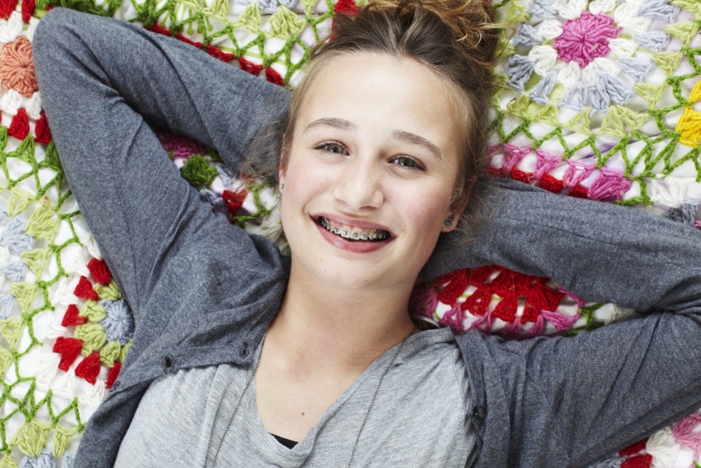 Teeange girl with braces lying on a blanket