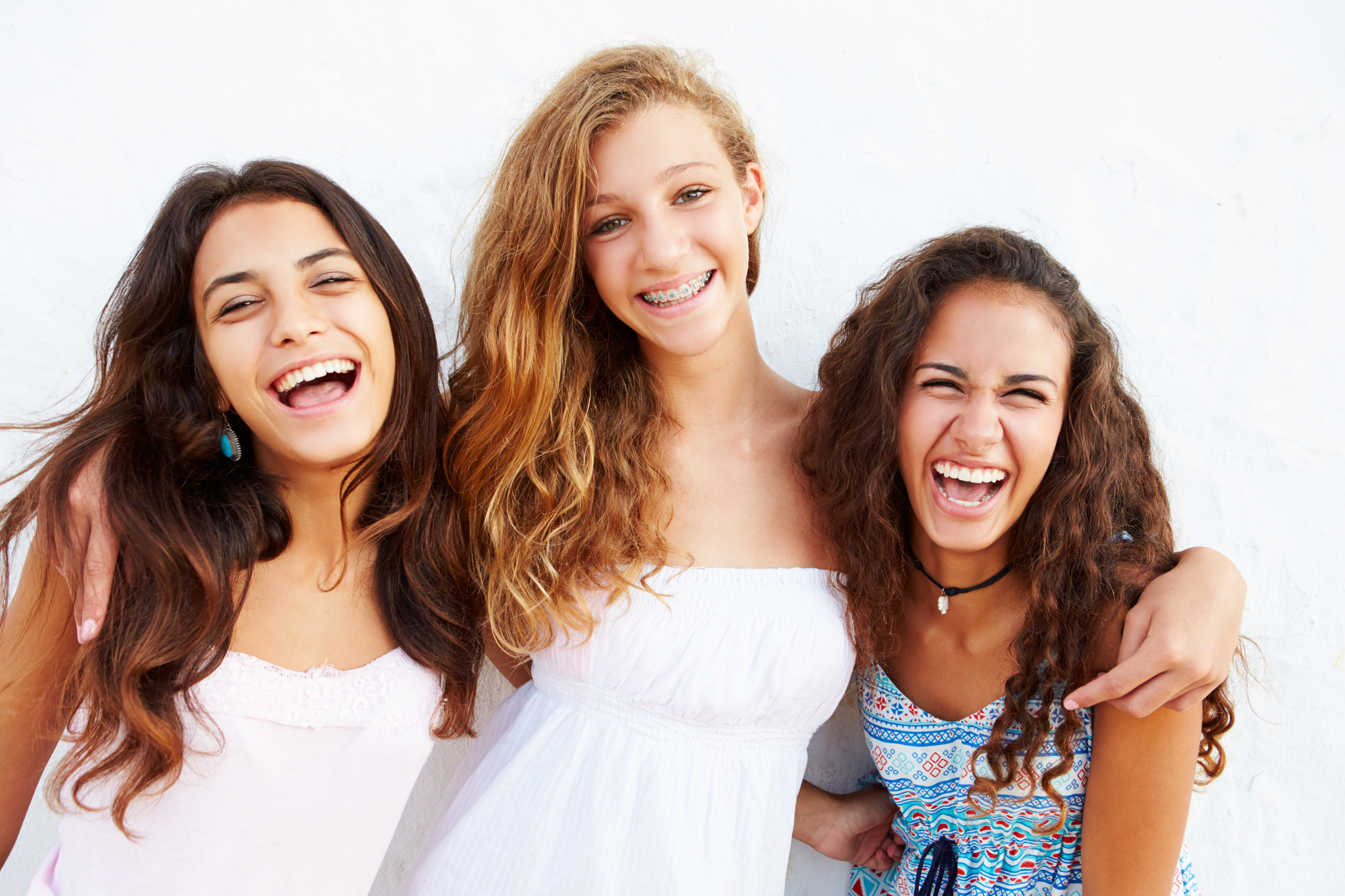 Portrait Of Three Teenage Girls Laughing and Leaning Against Wall