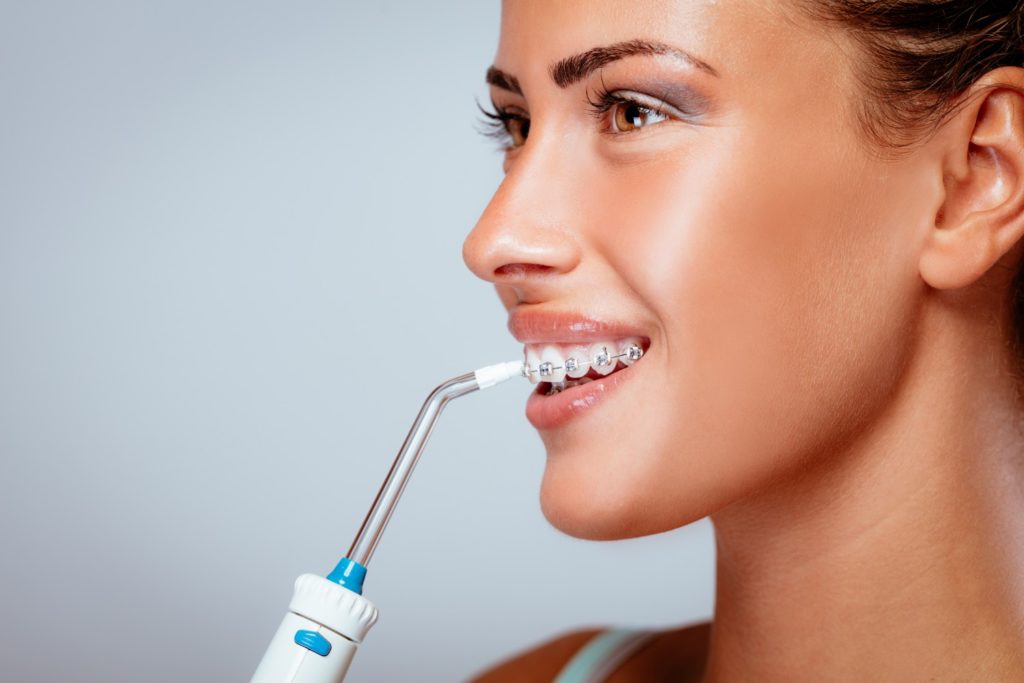 women flossing braces with water flosser